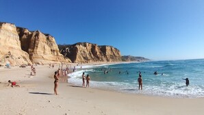 Une plage avec un ciel dégagé, un rivage sablonneux et des falaises rocheuses.
