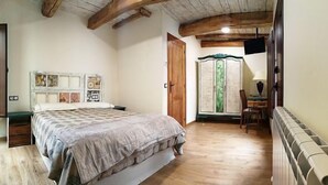Un dormitorio con cama, suelo de madera, un armario y un escritorio con silla.