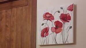 Una puerta de madera y una pared con un cuadro de flores rojas.