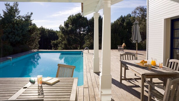 A wooden deck with a pool, outdoor furniture, and a covered patio area. - Piscine Privée! Villa charmante proche du Golf (Moliets)