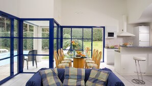 A modern kitchen with a dining area, large windows, and a view of a pool. - Piscine Privée! Villa charmante proche du Golf (Moliets)