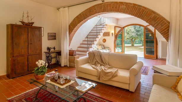 Ein geräumiges Wohnzimmer mit großem, rundbogigen Durchgang zu einer Treppe und einem Garten.