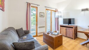 A living room with a grey sofa, wooden coffee table, and a TV on a wooden cabinet.