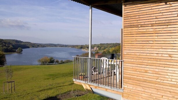 A wooden building with a balcony overlooking a lake.