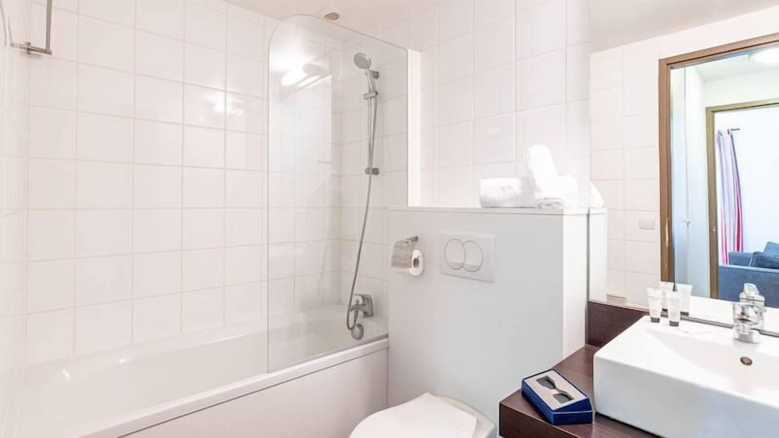 A modern bathroom with a glass-enclosed shower, a toilet, and a sink with toiletries.