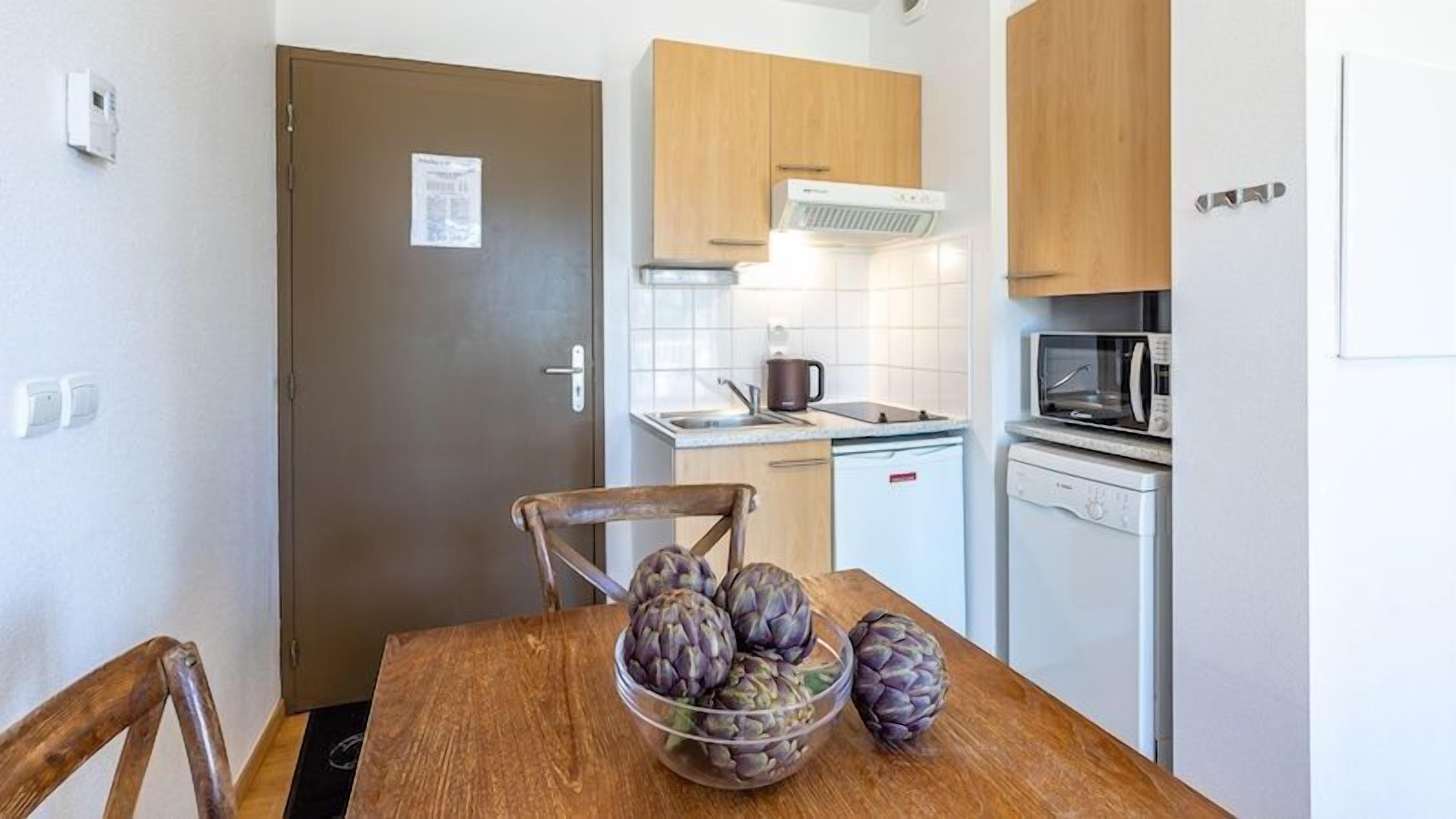 Une cuisine compacte avec des meubles en bois, un four à micro-ondes, un évier et un petit réfrigérateur.