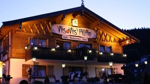 A wooden building with a sign reading "Vis & Vis's Hütte" indicating it is a cafe, restaurant, and inn.