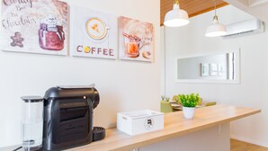 A modern kitchen with a coffee machine, a water dispenser, and a white cabinet. There are three coffee-themed wall art pieces above the counter. - Spacious 3BR / 2 bath | Historic center Braga (Braga)