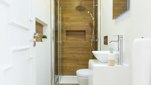 A modern bathroom with a glass-enclosed shower, a white toilet, and a sink with a mirror above it. - Spacious 3BR / 2 bath | Historic center Braga (Braga)