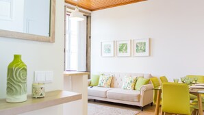 A modern living room with a sofa, a dining table with chairs, a large window, and framed wall art. - Spacious 3BR / 2 bath | Historic center Braga (Braga)