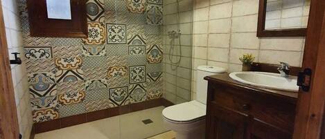 A bathroom with patterned tiles, a toilet, a sink, and a wooden cabinet.