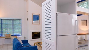 A modern kitchen with a white Bosch refrigerator, a dining area with a blue sofa, and a window with blue blinds.