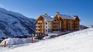 A multi-story hotel with a ski slope in the background.