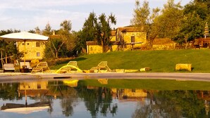 A serene lakeside setting with a gazebo, lounge chairs, and a stone building. - VILLA WITH 6 APARTMENTS 23 SEATS BEDS (Radicondoli)
