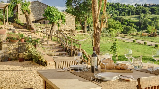 An outdoor dining area with a table set for a meal, overlooking a stone staircase and lush greenery. - VILLA WITH 6 APARTMENTS 23 SEATS BEDS (Radicondoli)