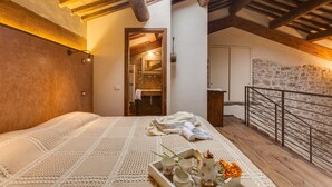 A cozy bedroom with a wooden ceiling, a stone wall, and a balcony railing. - VILLA WITH 6 APARTMENTS 23 SEATS BEDS (Radicondoli)