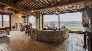 A rustic room with a large window, wooden beams, a round table, and a cozy bed. - VILLA WITH 6 APARTMENTS 23 SEATS BEDS (Radicondoli)