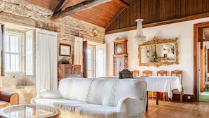 A rustic room with a high wooden ceiling, stone walls, a white sofa, a round table, and a dining table with chairs. - Quinta do Loureiro  Douro  Baião  Private  Pool  Stunning Views  Full privacy . (Santa Leocádia)