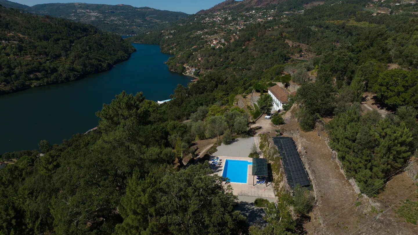 Propiedad con piscina, paneles solares y vistas a una cascada.