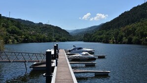 A wooden dock extending into a calm lake surrounded by hills, with several boats docked at the pier. - Quinta do Loureiro  Douro  Baião  Private  Pool  Stunning Views  Full privacy . (Santa Leocádia)