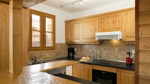 Una cocina con armarios de madera, encimera negra, estufa integrada y ventana con vistas al exterior.