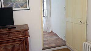 Ein Flur mit einem Holzkabinett, einem gerahmten Bild und einer Tür zu einem Zimmer.