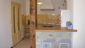 Eine Küche mit Stein Arbeitsplatte, zwei Barhocker, einer Spüle und einem Kühlschrank.