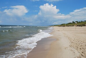 A beach with waves, a clear sky, and a sandy shore.