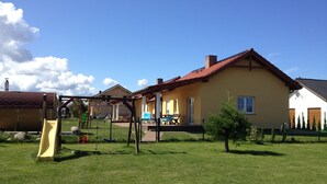 Ein Haus mit rotem Ziegeldach, einem umzäunten Garten und einem kleinen Baum.