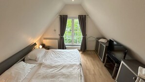 A bedroom with two beds, a desk, a TV, and a window with curtains. - Maisonette apartment 70m² with 2x shower / WC and 2 bedrooms Central WLAN (Zingst)