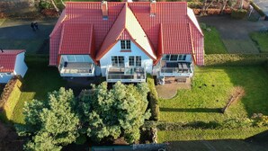 A large house with a red roof, multiple balconies, and a well-maintained lawn. - Maisonette apartment 70m² with 2x shower / WC and 2 bedrooms Central WLAN (Zingst)