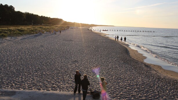 A wide beach with a gentle curve, a pier extending into the water, and people walking along the shore. - Maisonette apartment 70m² with 2x shower / WC and 2 bedrooms Central WLAN (Zingst)