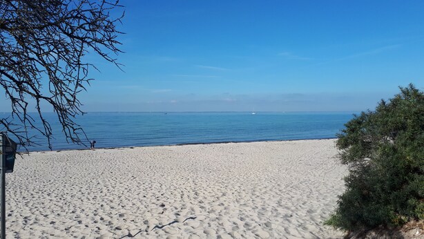 Une plage de sable blanc, sous un ciel bleu azur.