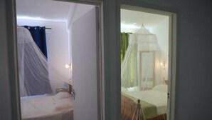 Een slaapkamer met een bed dat bedekt is door een wit hemelbed en een apart hemelbed.