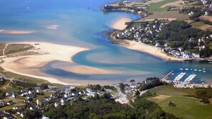 Vue aérienne d’une ville côtière avec des plages de sable, un phare et un port de plaisance.