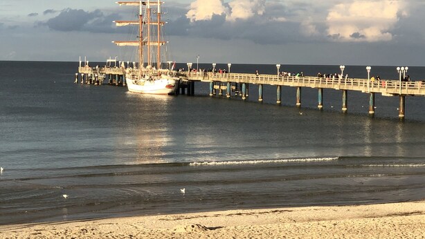 Un muelle se adentra en aguas tranquilas, con un barco de gran tamaño amarrado al final.