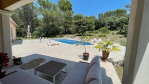 Zona piscina con sedie a sdraio, un tavolino e piante in vaso.