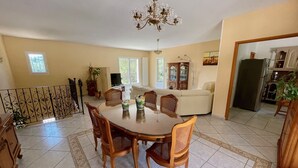 Un'area pranzo con un tavolo rotondo, sei sedie di legno e un lampadario.