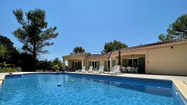 Una piscina con lettini, un portico coperto e un edificio con tetto in tegole.