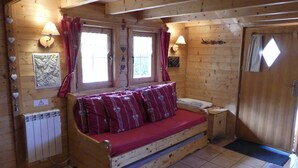 A cozy wooden cabin room with a bed, two windows with curtains, a radiator, and wall decorations. - 538 sq ft chalet for 4 persons in Saint Gervais Mont-Blanc (Saint-Gervais-Les-Bains)
