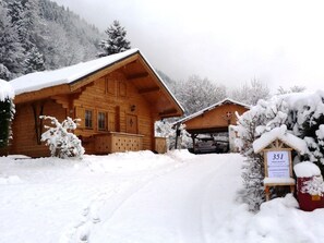 Un chalet en bois dont le toit est recouvert de neige, avec un garage et une pancarte indiquant le numéro de chambre 351.