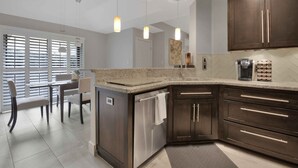 Una cocina moderna con armarios de madera oscura, encimera de granito e iluminación colgante.