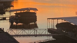 Auringonlaskunäkymä tyynen järven yllä, jossa on laiturissa olevia veneitä ja laituri.