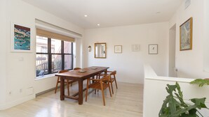 A dining area with a wooden table and chairs, large windows with blinds, and artwork on the walls. - Beautiful apartment with balconies and views, near park and museums in Nolita (New York)