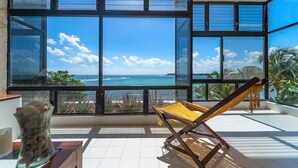 Un balcon avec vue sur l’océan, une chaise et un vase.
