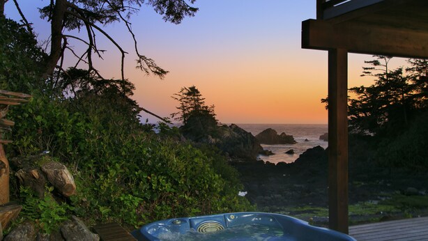 Uma banheira de hidromassagem com vista para o oceano ao pôr do sol.