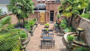 A brick patio with outdoor furniture, surrounded by lush greenery and a brick wall. -  Jones St Hist Dist Gem 1853- 3KgBd/3Ba exquisite courtyard- 50 %offSun -ThurNts (Savannah)