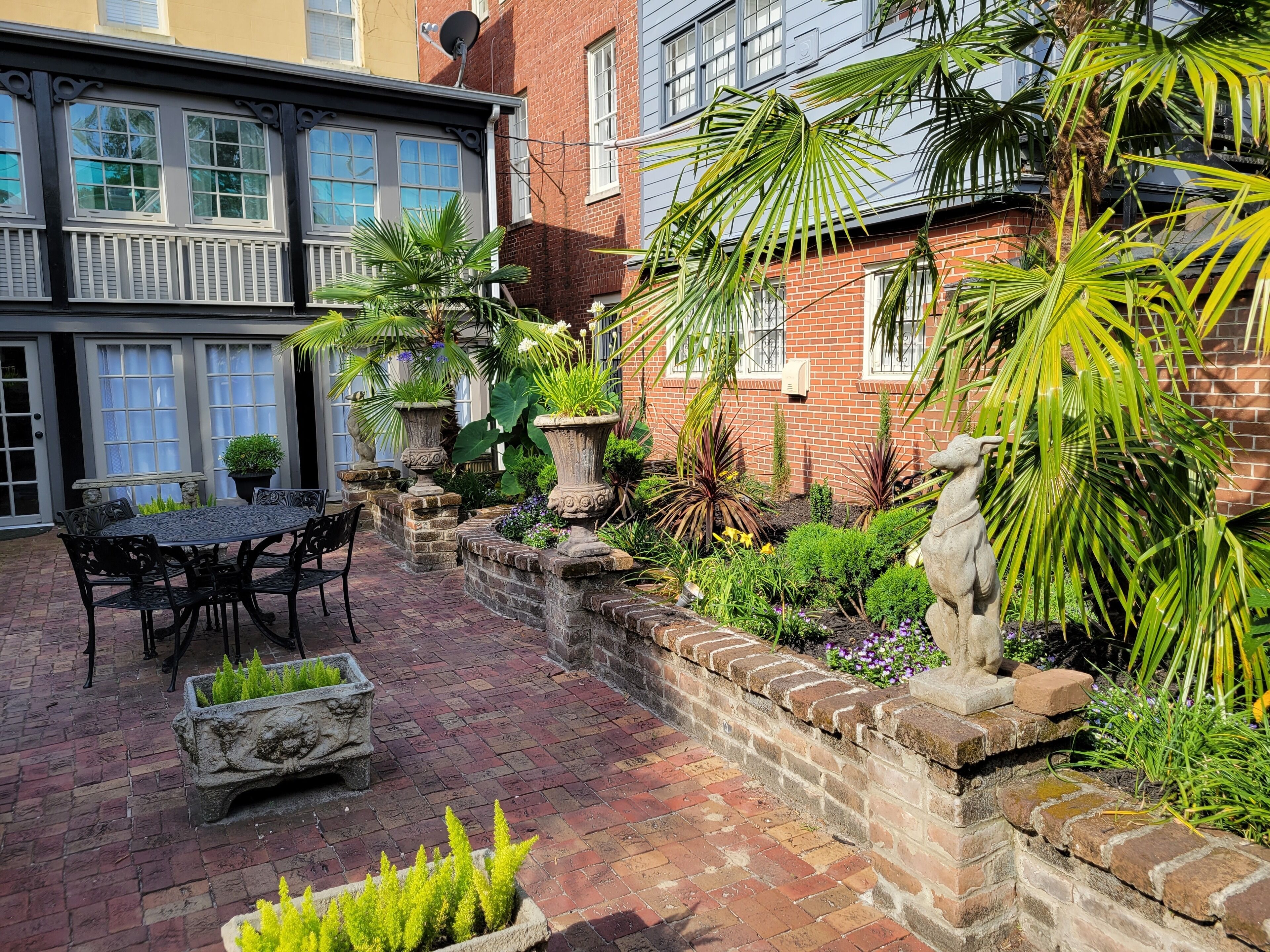 A courtyard with a brick patio, outdoor seating, and potted plants.