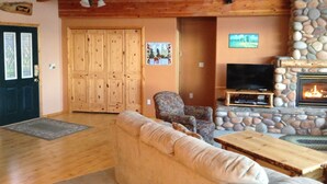 Una sala de estar acogedora con chimenea de piedra, muebles de madera y un televisor.
