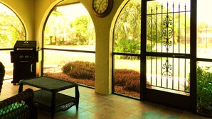 A covered patio with a ceiling fan, a clock, and a view of a garden through a gate. - Only 3-Miles to Gulf Beaches - Swim, Play Tennis or Just Relax (Bonita Springs)